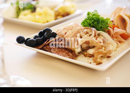 Le menu mariage présente une variété de hors-d'œuvre sur une table élégamment dressée, mettant en évidence des sélections gastronomiques et des garnitures colorées pour une ambiance festive Banque D'Images