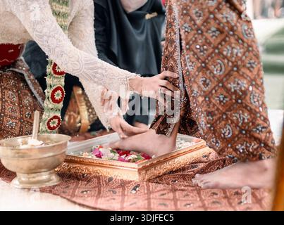 Procession traditionnelle javanaise de la mariée versant de l'eau de fleur aux pieds du marié Banque D'Images