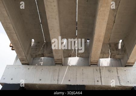 Vue rapprochée du dessous d'un pont en béton en construction montrant des poutres précontraintes parallèles, des interstices structurels et des détails en béton armé brut Banque D'Images