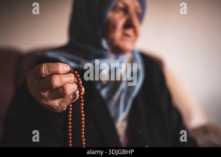 La vieille femme musulmane tient le chapelet dans ses mains, faisant la prière zikr avec des perles de prière traditionnelles. Banque D'Images