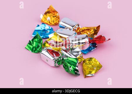 Sucreries savoureuses dans des emballages colorés sur rose. Banque D'Images