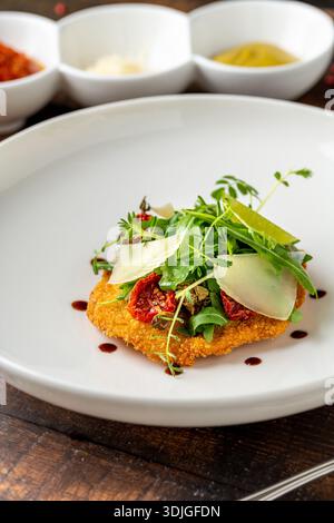 Escalope de veau panée servie avec herbes et fromage sur assiette Banque D'Images