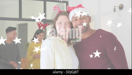 Couple souriant posant à la maison, portant un pull marron, une veste jaune clair et un motif étoilé. Festif, vacances, décor, arbre, rassemblement, amis Banque D'Images