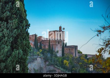 Vue sur l'ancienne forteresse debout majestueusement au sommet d'une colline, ses murs de pierre altérés captant la lumière dorée du soleil contre le ciel bleu clair, GRA Banque D'Images