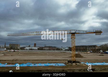 Grue à tour sur un chantier de construction urbaine sous un ciel gris nuageux, atmosphère industrielle et développement urbain moderne Banque D'Images