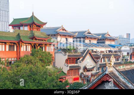 Bâtiment chinois traditionnel aux toits en tuiles vertes et aux détails architecturaux ornés entouré d'un paysage urbain moderne. Architecture de temple chinois dans Banque D'Images