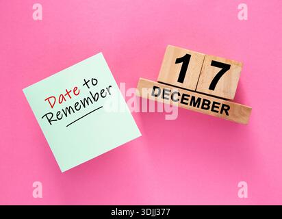 Note collante à côté d'un calendrier de bloc de bois montrant le 17 décembre sur fond rose Banque D'Images