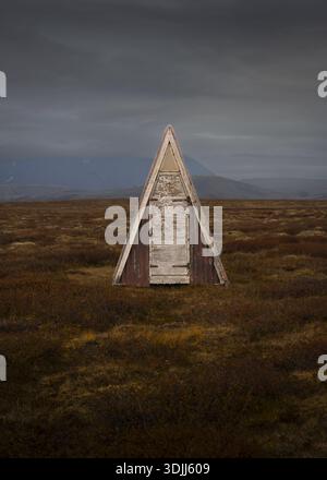Vue d'une structure triangulaire frappante, altérée et dure, s'élève des herbes ocres sous un ciel couvant, une sentinelle solitaire, Tórshavn, Féroé Banque D'Images