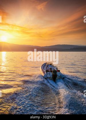 Vue aérienne d'un bateau à moteur RIB naviguant dans le coucher de soleil d'été doré avec la mer calme Banque D'Images
