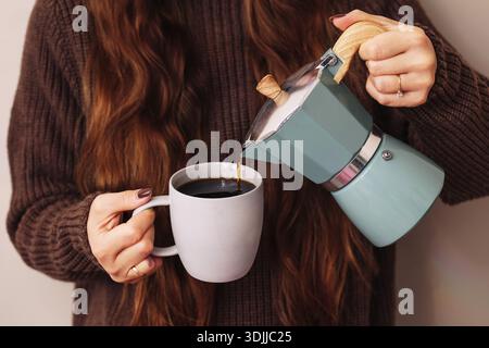 Verser le café du pot de moka dans la tasse. Préparation de boissons chaudes maison. Routine matinale agréable avec espresso fraîchement préparé. Moment de style de vie à la maison. Banque D'Images