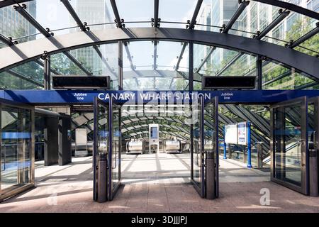 Une vue large de l'entrée moderne en verre et en acier de la station de métro Canary Wharf, montrant la symétrie architecturale et la ligne Jubilee Banque D'Images