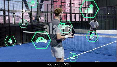 Tenant la pagaie, homme portant une chemise grise et une bande préparant servir sur le terrain bleu, avec des icônes vertes. Padel, tennis, athlète, duo, urbain, installation, traini Banque D'Images