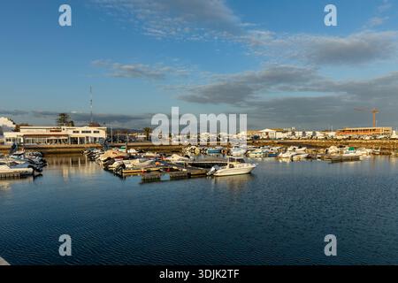 Vue panoramique sur la marina et le port de Olhão, Algarve, Portugal. Les petits bateaux sont amarrés sur l'eau bleue calme près de l'entrée du port, avec por Banque D'Images