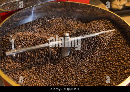 Le café est torréfié à la main dans un petit torréfacteur à tambour avec beaucoup d'expérience, où les grains de café chauds fraîchement torréfiés refroidissent en utilisant l'air dans un tamis, Banque D'Images