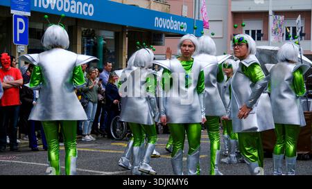 13 février 2024 - Torres Vedras, Portugal : groupe de participants à la procession de carnaval en costumes sur le thème du cosmos ou extraterrestres défilant dans la rue de la ville et vérifiant si d'autres participants, téléspectateurs et visiteurs apprécient l'événement sur les trottoirs Banque D'Images