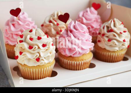 Bonne Saint Valentin. Savoureux cupcakes avec des coeurs rouges dans une boîte, gros plan Banque D'Images