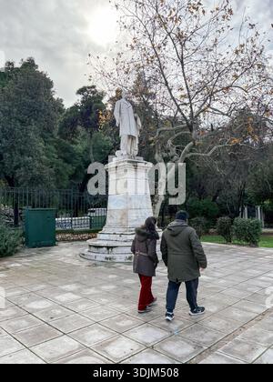 Statue de Charilaos Trikoupis, influent premier ministre grec. Deux personnes marchant devant le monument dans une place publique ou un parc, Athènes, Grèce. Banque D'Images