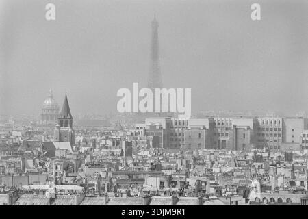 3 août 1990 : la Tour Eiffel s'élève au-dessus d'un horizon parisien brumeux, vue sur les toits de la ville. Photographie vintage en noir et blanc. Banque D'Images