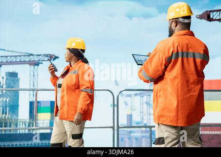 Équipe d'ingénieurs de plate-forme offshore utilisant l'application tablette pour surveiller les performances de l'équipement en temps réel. Les employés de l'engin de forage étalonnent l'infrastructure avec le système de gestion des actifs sur l'appareil Banque D'Images