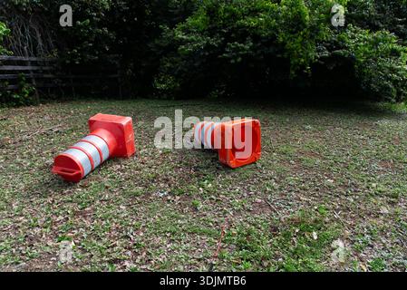 Salvador, Bahia, Brésil - 25 janvier 2026 : deux cônes orange et argentés gisant sur une pelouse sèche près des bois. Banque D'Images