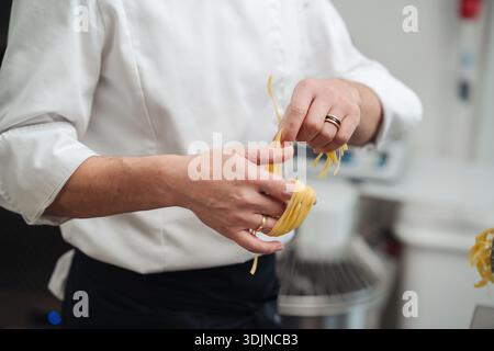 Chef de pâtes caucasien formant des nids de tagliatelles à la main Banque D'Images