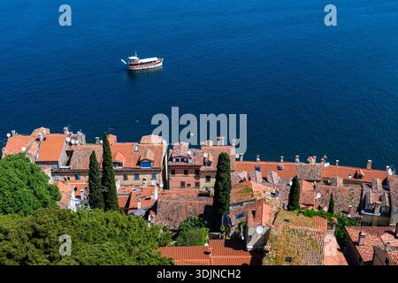 Vue panoramique depuis le clocher de l'église de l'Euphemia sur des maisons aux toits rouges et un petit bateau sur la mer Adriatique bleue au loin. Banque D'Images
