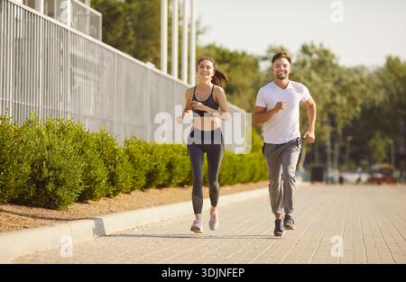 Sport fit homme et femme couple courir souriant ensemble sur le chemin pavé à l'extérieur, exercice heureux Banque D'Images