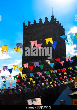 La tour du château de Lubart s'élève contre un ciel bleu vif, avec des drapeaux triangulaires colorés du festival enfilés au premier plan, créant un atmos vibrant Banque D'Images