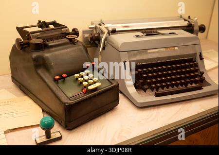 Présentoir de bureau vintage avec une calculatrice mécanique et une machine à écrire Olivetti Linea 88, aux côtés d'un tampon à encre et de vieux papiers Banque D'Images