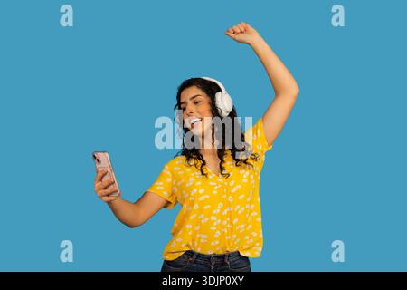 Jeune femme dansant joyeusement tout en portant des écouteurs et en tenant un téléphone Banque D'Images