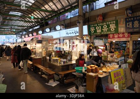 Séoul, Corée du Sud : stands de nourriture très fréquentés et visiteurs marchant à travers le marché de Gwangjang, l'un des plus anciens marchés traditionnels de la ville Banque D'Images