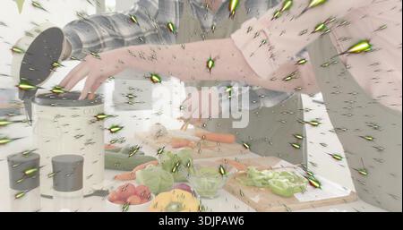 Couple préparant des légumes dans la cuisine à la maison, femme en haut rose, tablier vert, planche, étoile verte Banque D'Images