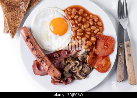 Petit-déjeuner anglais complet avec oeuf frit, bacon, saucisses et haricots isoaltérés sur fond blanc Banque D'Images
