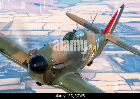 Le Hawker Hurricane Mk I portant l'immatriculation G‑HRLI et le numéro de série V7497 avec le code SD‑X est montré dans une photographie air‑air en gros plan à UK Warbirds 2022. Peint aux couleurs de l'armée de l'air britannique, ce chasseur britannique restauré de la seconde Guerre mondiale est propulsé par un moteur à pistons Rolls‑Royce Merlin III V12 et dispose d'un cockpit monoplace et d'un fuselage robuste. Son armement fixe et sa conception historique reflètent son rôle clé dans les premières opérations aériennes alliées. Banque D'Images