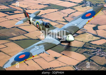 Vue rapprochée air-air d'une variante Seafire Supermarine Spitfire LF Mk Vc construite par Westland et volée pendant UK Warbirds 2022. L'avion est immatriculé G-IBSY et fini dans les marques d'affichage de la Royal Air Force avec le code DV-V. Il est propulsé par un moteur à pistons V-12 Rolls-Royce Merlin 45 refroidi par liquide entraînant une hélice à trois pales. Les caractéristiques visibles comprennent la verrière encadrée, les ailes elliptiques, le capot moteur, les cheminées d'échappement et les détails de la cellule Spitfire du début de la guerre conservés pour les opérations de vol historiques. Banque D'Images