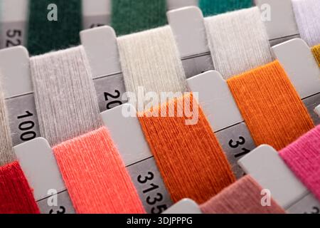 Une vue en gros plan, en grand angle, montre un tableau organisé d'échantillons de carton rectangulaires enveloppés dans différents fils de couleur, chacun marqué d'un i noir Banque D'Images