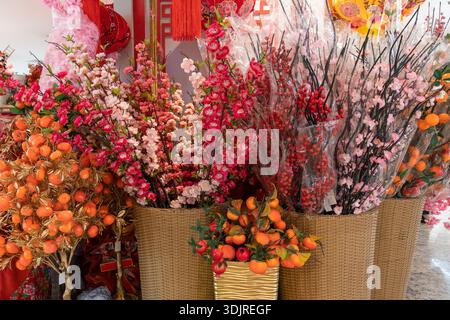 Motif floral artificiel coloré orné de fleurs roses, rouges et orangées disposées dans des paniers tissés. Le décor saisonnier lumineux évoque la fête Banque D'Images