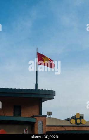 Drapeau national vietnamien flottant au sommet d'un bâtiment de montagne à Ba Den Mountain, Tay Ninh, Vietnam, symbolisant la fierté nationale contre un ciel bleu clair. Banque D'Images