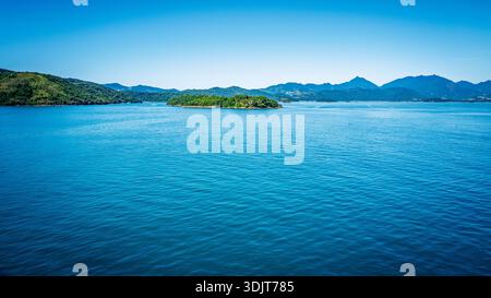 Un paysage marin serein avec des eaux calmes et bleu profond menant à une chaîne d'îles verdoyantes et couvertes d'arbres et de collines ondulantes. Banque D'Images
