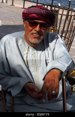 Portrait d'homme omanais portant un Musar et des lunettes de soleil souriant avec le Furakha attaché à la nuque de son Sultanat Dishdasha sur Oman d'Oman Banque D'Images