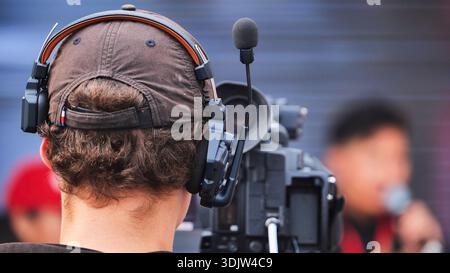 Cameraman portant un casque avec un microphone actionnant une caméra vidéo pendant un événement. Banque D'Images