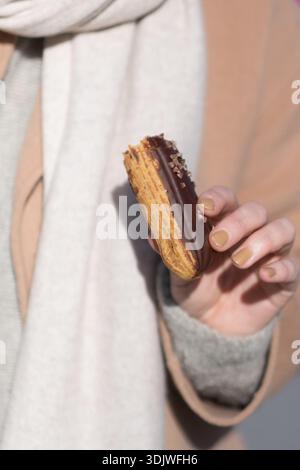 Femme tenant une pâtisserie Eclair, dessert de pâtisserie française en gros plan, snack sucré à Paris, France. Banque D'Images