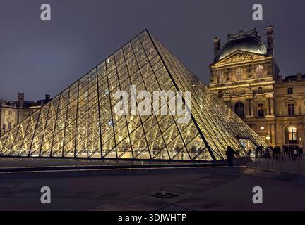 Photo de nuit de la pyramide de verre et du palais traditionnel dans la cour intérieure du Musée du Louvre - Paris, France Banque D'Images