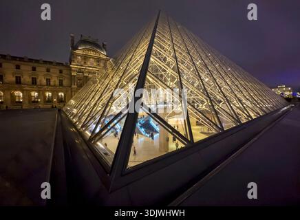 Photo de nuit de la pyramide de verre et du palais traditionnel dans la cour intérieure du Musée du Louvre - Paris, France Banque D'Images