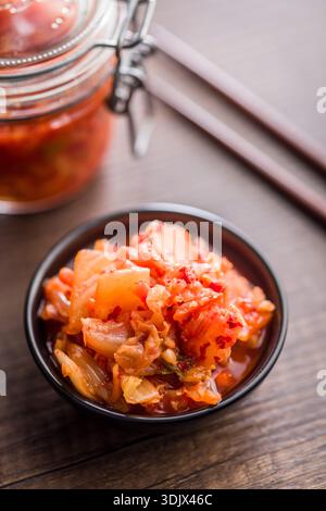 Chou fermenté. Kimchi. Nourriture coréenne dans un bol sur une table en bois. Banque D'Images