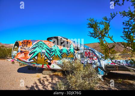 Graffiti recouvert le fuselage d'un avion abandonné dans le désert du Nevada avec des arbustes Banque D'Images