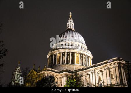 Vue architecturale nocturne d'une cathédrale à dôme grandiose illuminée contre un ciel sombre. L'éclairage dramatique met en évidence des pierres complexes, des colonnes Banque D'Images