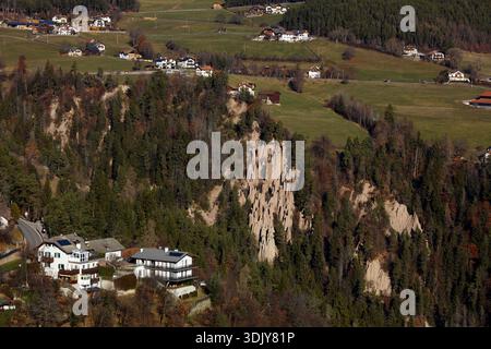 Un hôtel et des maisons près des pyramides de la Terre de Ritten (Renon), un monument naturel situé sur un plateau près de Klobenstein dans le Tyrol du Sud, Italie. Banque D'Images