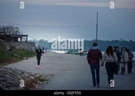 BELGRADE, SERBIE - 9 NOVEMBRE 2025 : femme court le long de la promenade du quai de Zemun à Belgrade, Serbie par le danube, tandis que les piétons marchent à proximité, Banque D'Images