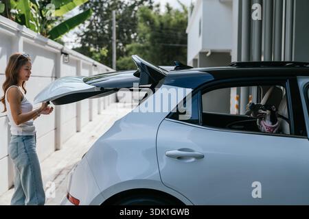 Femme ouvrant le coffre de voiture avec le chien à l'intérieur Banque D'Images